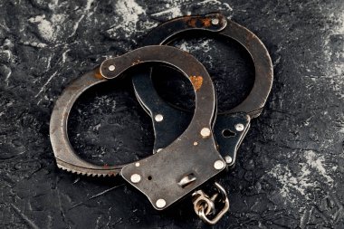 Koyu bir arka planda kelepçeler. Suç ve polis kavramı.