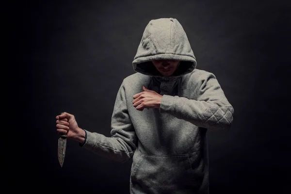 Un uomo con un coltello si copre il viso con la mano nello Studio o — Foto Stock