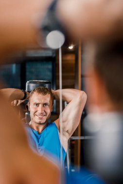 Genç kaslı adam spor salonundaki halterlerle egzersiz yapıyor..