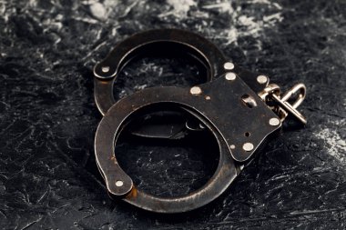 Koyu bir arka planda kelepçeler. Suç ve polis kavramı