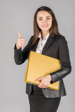 Koyu renk süitte gri arka planı olan genç bir iş kadını. Ofis kavramı