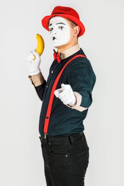 Kırmızı pantolon askısı ve beyaz arka planda kırmızı şapkası olan palyaço..