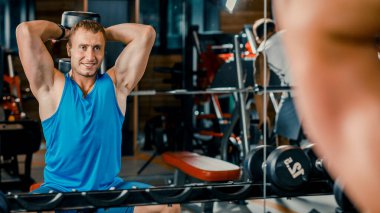 Genç kaslı adam spor salonundaki halterlerle egzersiz yapıyor..