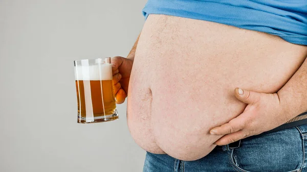 A man with a fat belly holding a glass of beer. On gray background