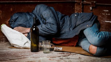 Evsiz bir adam, bir sarhoş, sokakta uyuyakaldı. Alkolizm ve evsizlik kavramı.