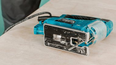 İşçi elektrikli bir yap-boz ile tahtaları keser, toz her yöne uçar. İnşaat ve onarım kavramı