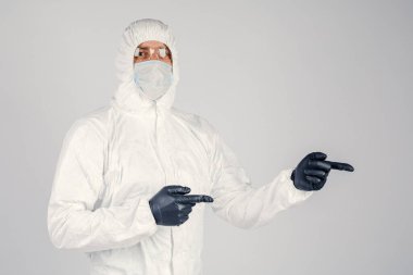 Tek kullanımlık anti-bakteriyel izolasyon giysisi içindeki bir insan epidemiyoloğu beyaz arka planda el hareketlerini gösteriyor. Salgın ve tıbbi konsept.