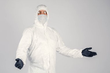 Tek kullanımlık anti-bakteriyel izolasyon giysisi içindeki bir insan epidemiyoloğu beyaz arka planda el hareketlerini gösteriyor. Salgın ve tıbbi konsept.