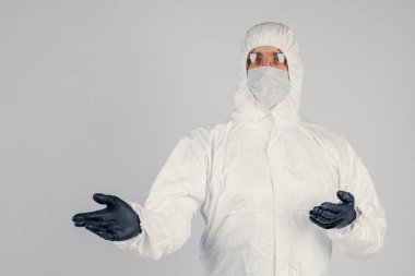 Tek kullanımlık anti-bakteriyel izolasyon giysisi içindeki bir insan epidemiyoloğu beyaz arka planda el hareketlerini gösteriyor. Salgın ve tıbbi konsept.