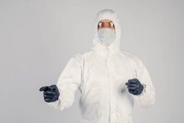 Tek kullanımlık anti-bakteriyel izolasyon giysisi içindeki bir insan epidemiyoloğu beyaz arka planda el hareketlerini gösteriyor. Salgın ve tıbbi konsept.