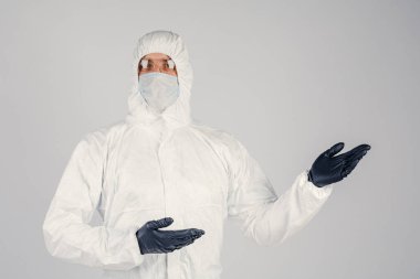 Tek kullanımlık anti-bakteriyel izolasyon giysisi içindeki bir insan epidemiyoloğu beyaz arka planda el hareketlerini gösteriyor. Salgın ve tıbbi konsept.