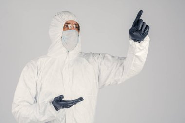 Tek kullanımlık anti-bakteriyel izolasyon giysisi içindeki bir insan epidemiyoloğu beyaz arka planda el hareketlerini gösteriyor. Salgın ve tıbbi konsept.