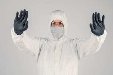 Tek kullanımlık anti-bakteriyel izolasyon giysisi içindeki bir insan epidemiyoloğu beyaz arka planda el hareketlerini gösteriyor. Salgın ve tıbbi konsept.