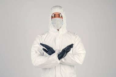 Tek kullanımlık anti-bakteriyel izolasyon giysisi içindeki bir insan epidemiyoloğu beyaz arka planda el hareketlerini gösteriyor. Salgın ve tıbbi konsept.