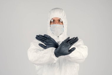 Tek kullanımlık anti-bakteriyel izolasyon giysisi içindeki bir insan epidemiyoloğu beyaz arka planda el hareketlerini gösteriyor. Salgın ve tıbbi konsept.