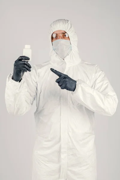 A man in a medical protective mask, holding a hand sanitizer