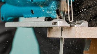 İşçi elektrikli bir yap-boz ile tahtaları keser, toz her yöne uçar. İnşaat ve onarım kavramı