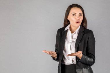 Gri arka planda, koyu renk süitte genç bir iş kadını. Ofis kavramı