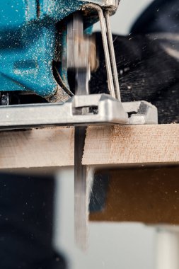 İşçi elektrikli bir yap-boz ile tahtaları keser, toz her yöne uçar. İnşaat ve onarım kavramı