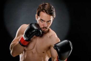 Boks eldivenli bir adam. Siyah arka planda boks yapan bir adam. Sağlıklı yaşam tarzı kavramı.