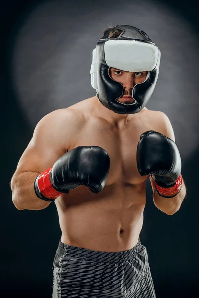 一个带着拳击头盔和手套的年轻男子在深色背景下的画像 — 图库照片