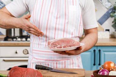 Genç ve güzel bir erkek şef mutfakta yemek sunar.