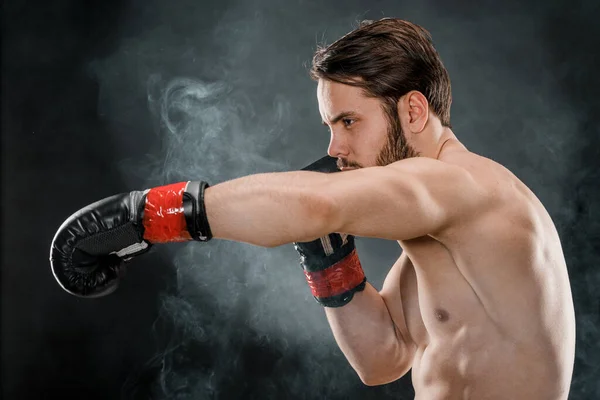 A man in Boxing gloves. A man Boxing on a black background. The concept of a healthy lifestyle.