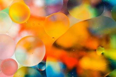 Su yüzeyindeki yağ damlacıklarının hareketine yakın çekim. Su yüzeyindeki yağ damlalarının renkli ve soyut makro arkaplanı