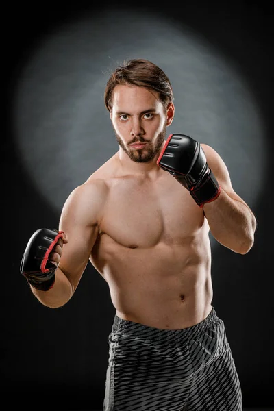 A man in Boxing gloves. A man Boxing on a black background. The concept of a healthy lifestyle.