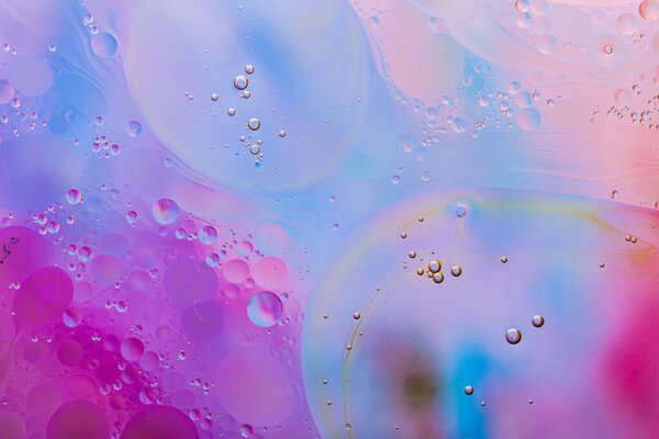 Крупный план движения капель масла по поверхности воды. Красочный абстрактный макрофон масляных капель на поверхности воды