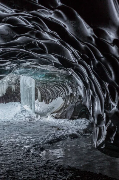 Ice wave. Black ice cave. Ice Grotto in Iceland. The structure of blue and black ice. Frozen waterfall in an ice cave.
