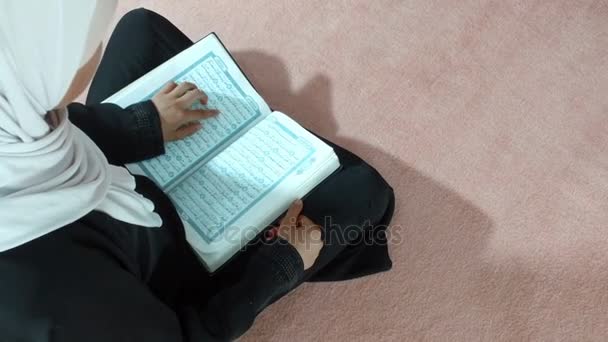 Un Musulman lit un Coran assis par terre. . — Video