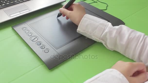 Een meisje zitten aan een tafel is geïnspireerd op een grafisch tablet. — Stockvideo