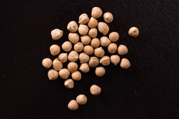 Placer chickpeas on a black background — Stock Photo, Image