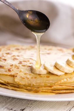 İnce krep muz ve bal ile. Maslenitsa. Hafif ahşap arka plan üzerinde Rus krep. Bir rustik tarzda.