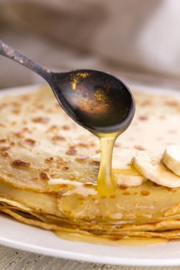 İnce krep muz ve bal ile. Maslenitsa. Hafif ahşap arka plan üzerinde Rus krep. Bir rustik tarzda.