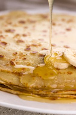 İnce krep muz ve bal ile. Maslenitsa. Hafif ahşap arka plan üzerinde Rus krep. Bir rustik tarzda.