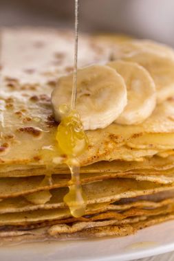 İnce krep muz ve bal ile. Maslenitsa. Hafif ahşap arka plan üzerinde Rus krep. Bir rustik tarzda.