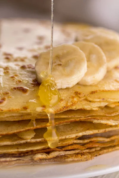 İnce krep muz ve bal ile. Maslenitsa. Hafif ahşap arka plan üzerinde Rus krep. Bir rustik tarzda.