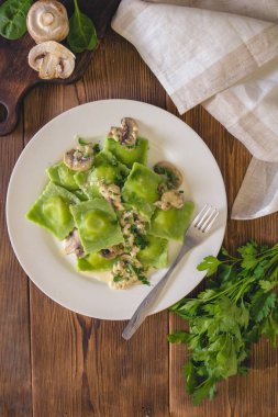 Champignon soslu peynirli ıspanak hamur ile lezzetli yeşil mantı dolma. İtalyan mutfağı.