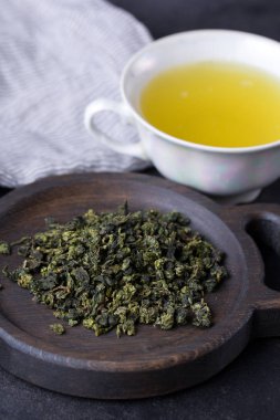 Bir fincan yeşil çay koyu arka plan üzerinde. Sıcak içecek yeşil çay bir porselen fincan çay yaprakları