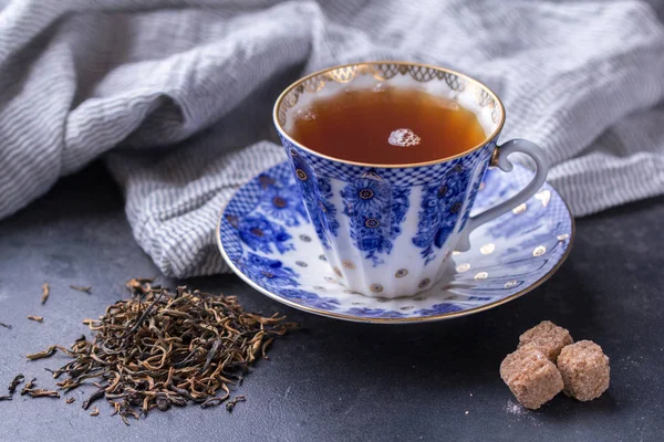 Porcelain cup of black tea on a dark background. Hot drink - black tea