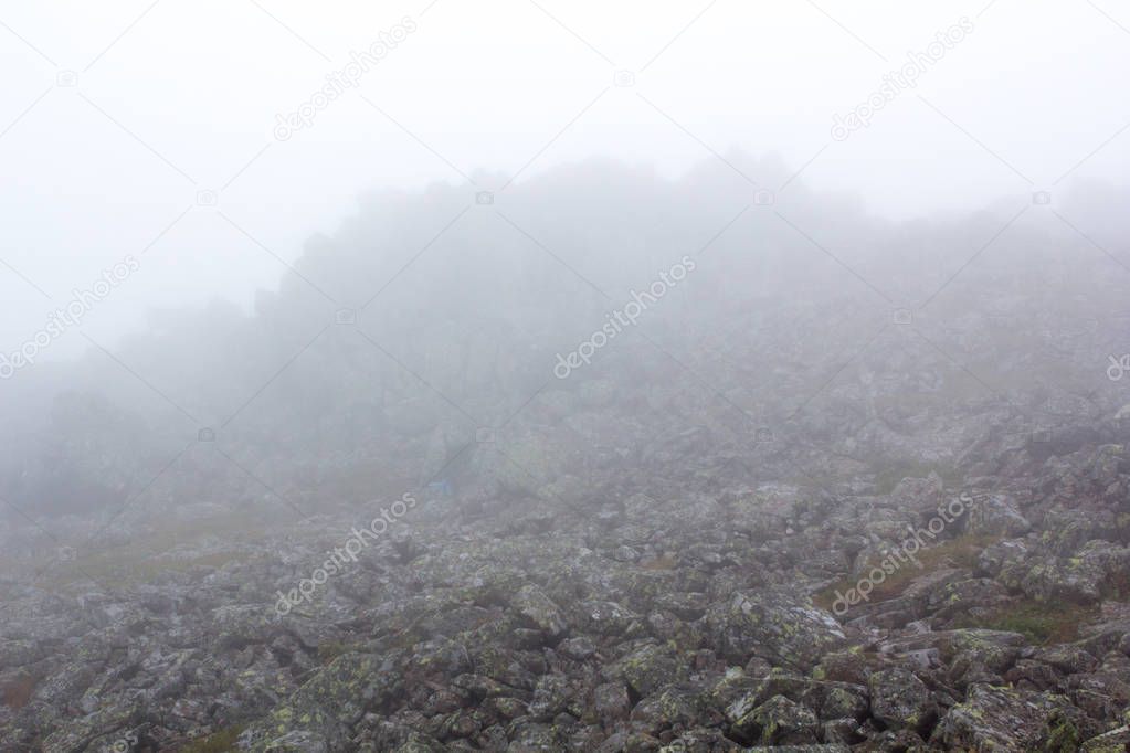 Gloomy mountain landscape. Fog in the mountains, the gloom comes down from the mountains. Mountain placer in the fog.