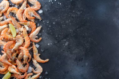 Kireç, buz ve deniz karides bir siyah arka plan üzerine tuz. Metniniz için çerçeve. Kireç ve siyah arka plan üzerine dağılmış baharatlar ile karides.