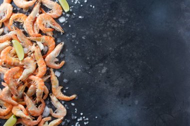 Kireç, buz ve deniz karides bir siyah arka plan üzerine tuz. Metniniz için çerçeve. Kireç ve siyah arka plan üzerine dağılmış baharatlar ile karides.
