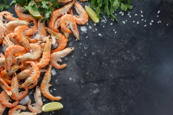 Gamberetti con lime, ghiaccio, erbe aromatiche e sale marino su fondo nero. Inquadra il tuo testo. Gamberetti con erbe e spezie sparsi su sfondo nero. Contesto alimentare . — Foto Stock