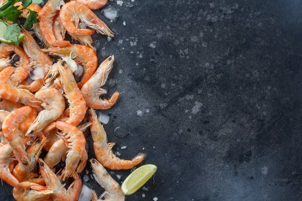 Crevettes avec citron vert, glace, herbes et sel de mer sur fond noir. Cadre pour votre texte. Crevettes aux herbes et épices éparpillées sur fond noir. Contexte alimentaire . — Photo