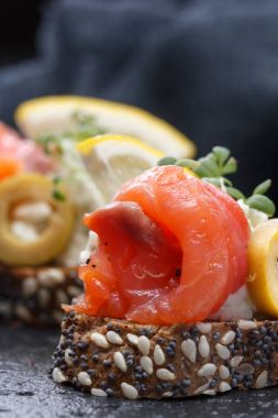 Karanlık bir arka plan üzerine somon ve peynir peynirli kanepe.