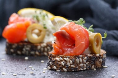 Karanlık bir arka plan üzerine somon ve peynir peynirli kanepe.