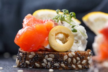 Karanlık bir arka plan üzerine somon ve peynir peynirli kanepe.